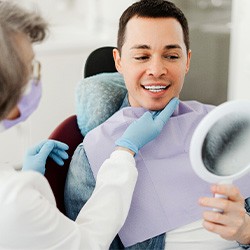 Man smiling at reflection in mirror with dentist