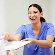 Dental assistant smiling while handing patient form