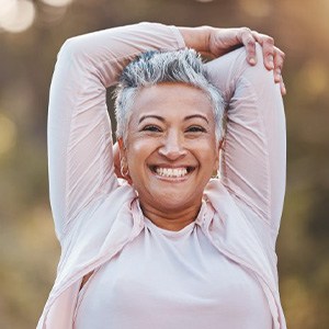 an older woman smiling while stretching before a hike