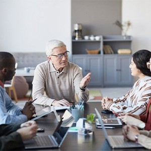 an older man conversing with colleagues