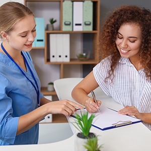 a front desk staff helping a patient fill out her paperwork